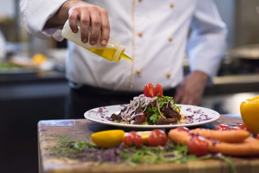 Chef finishing steak meat plate with Finally dish dressing and almost ready to serve at the table