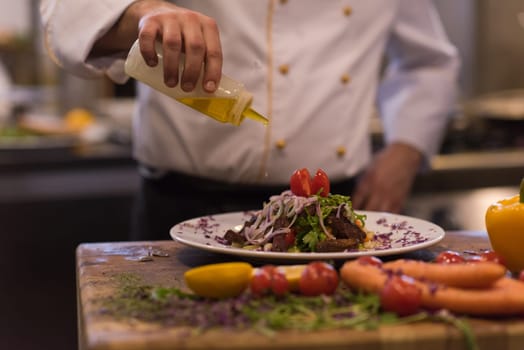 Chef finishing steak meat plate with Finally dish dressing and almost ready to serve at the table