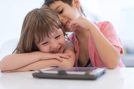 cute little brother and sister having fun at home childrends  playing games on tablet computer