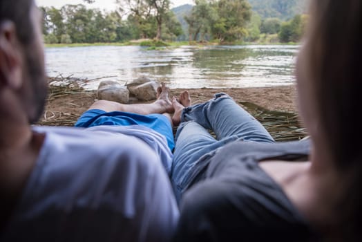 couple in love traveling and spending time together in straw tent while drinking hot tea by the river