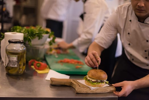 master chef putting toothpick on a burger in the kitchen