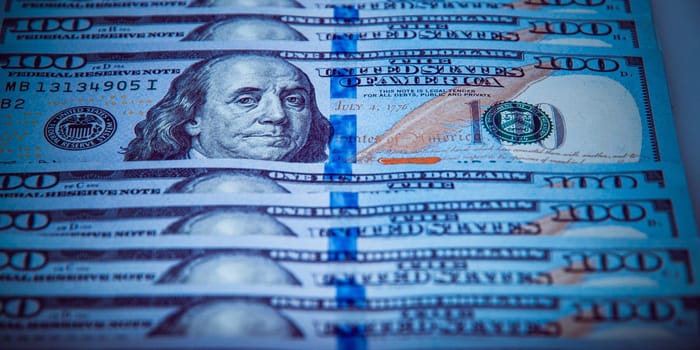 One hundred dollar bills are in a row, one stands out, selective focus. Style blue color.