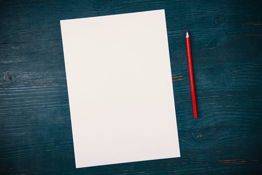 A blank white sheet and pencil for drawing on a wooden background with space for copying and lettering. Layout, mockup free space.