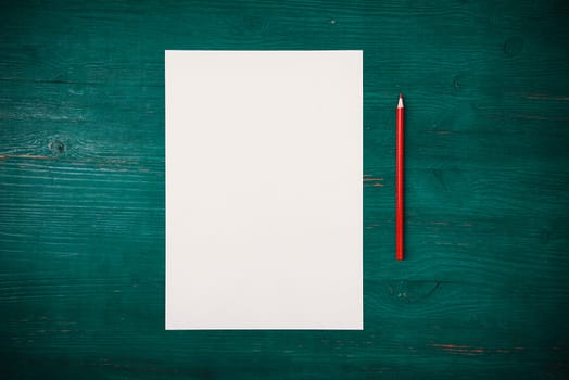 A blank white sheet and pencil for drawing on a wooden background with space for copying and lettering. Layout, mockup free space.