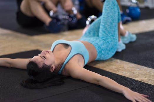 young athlete woman lying on the floor and relaxing before a hard training at cross fitness gym
