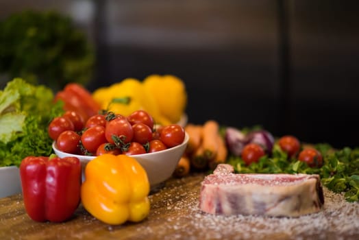Juicy slice of raw steak  with vegetables around on a wooden table