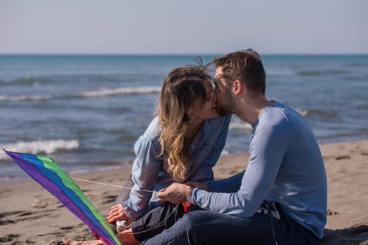 Young Couple having fun and Playing With A Kite On The Beach at autumn day