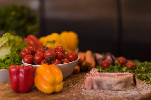 Juicy slice of raw steak  with vegetables on a wooden table