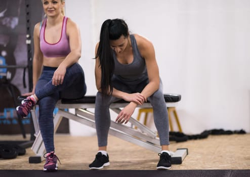 young athletes women sitting relaxing after exercise at cross fitness gym