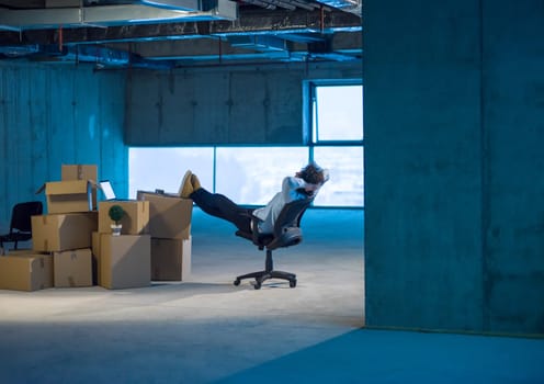 young businessman on construction site taking a break while checking documents and business workflow with cardboard boxes around him in new startup office