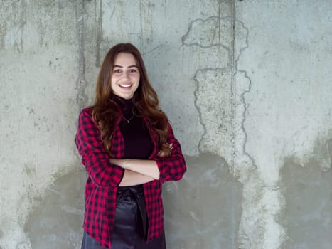 portrait of young successful smiling casual businesswoman standing in front of a concrete wall at new startup office