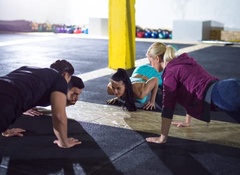 group of young healthy people doing pushups at fitness  gym