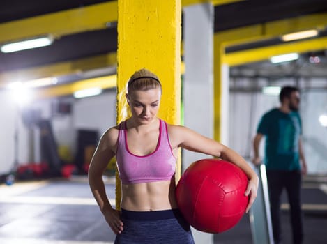 Portrait of beautiful athlete woman with red medicine  ball at crossfitness gym