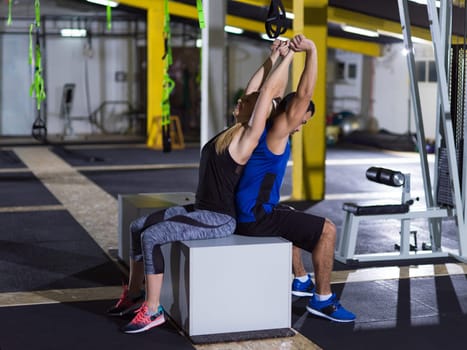 young couple athletes working out their arms using boxes at gym