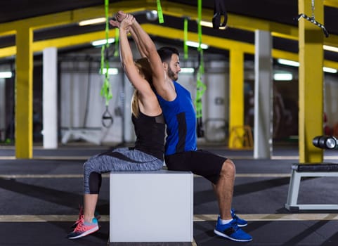 young couple athletes working out their arms using boxes at crossfitness gym