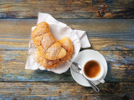 View from above. Cup of hot Italian espresso coffee and croissants on a light blue rustic wooden background. Food and drink. Lifestyle.