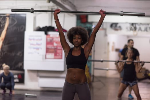 Young Cute african american sport woman in fitness room lifting empty bar