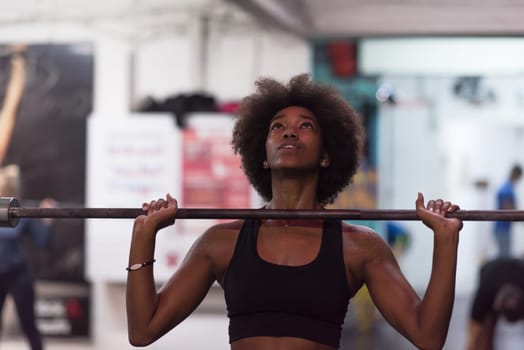 Young Cute african american sport woman in fitness room lifting empty bar