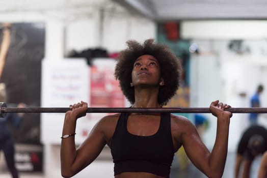 Young Cute african american sport woman in fitness room lifting empty bar