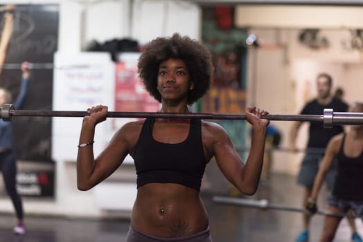 Young Cute african american sport woman in fitness room lifting empty bar