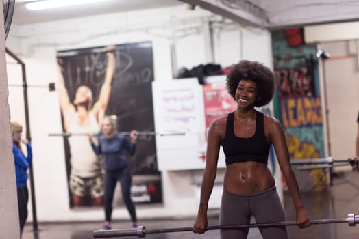 Young Cute african american sport woman in fitness room lifting empty bar