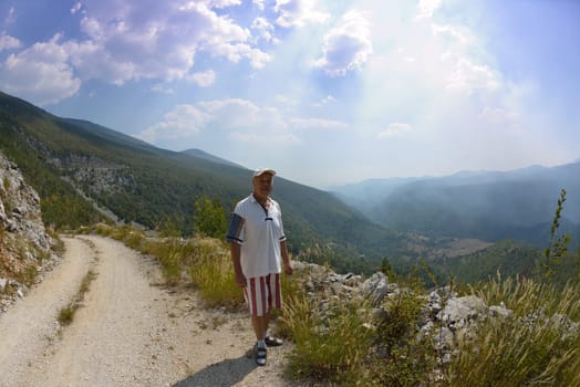 seinor male hiker relaxing in nature while  walking tour on beautiful summer day on canyon of  dried riverbed