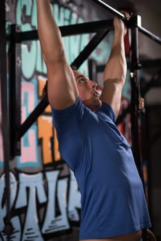 strong young man doing pull ups on a bar in a gym