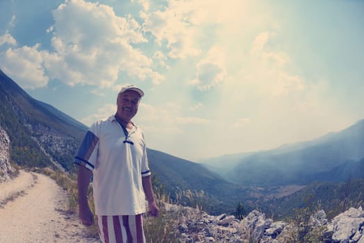 seinor male hiker relaxing in nature while  walking tour on beautiful summer day on canyon of  dried riverbed