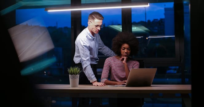 Multiethnic startup business team on meeting in modern night office interior brainstorming, working on laptop