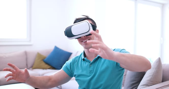 happy man getting experience using VR-headset glasses of virtual reality at home