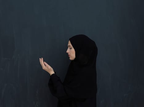 Portrait of young Muslim woman making dua. Arabian girl wearing abaya keeps hands in praying gesture. Representing worship to God and Ramadan Kareem concept