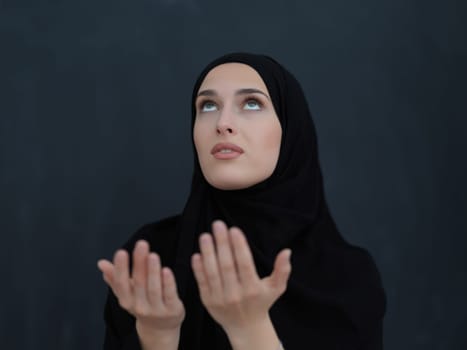 Portrait of young Muslim woman making dua. Arabian girl wearing abaya keeps hands in praying gesture. Representing worship to God and Ramadan Kareem concept