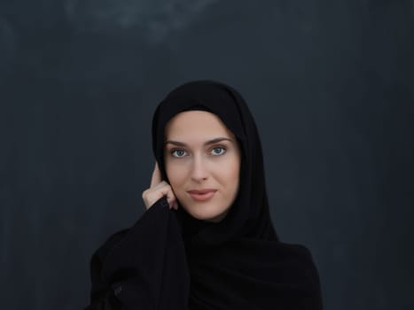 Young muslim businesswoman in traditional clothes or abaya talking on the smartphone. Arab woman in front of black chalkboard and representing techology, islamic fashion and Ramadan kareem concept