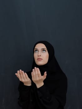 Portrait of young Muslim woman making dua. Arabian girl wearing abaya keeps hands in praying gesture. Representing worship to God and Ramadan Kareem concept