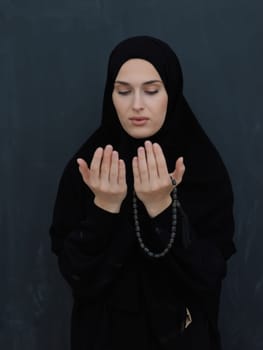 Portrait of young Muslim woman making dua. Arabian girl wearing abaya keeps hands in praying gesture. Representing worship to God and Ramadan Kareem concept