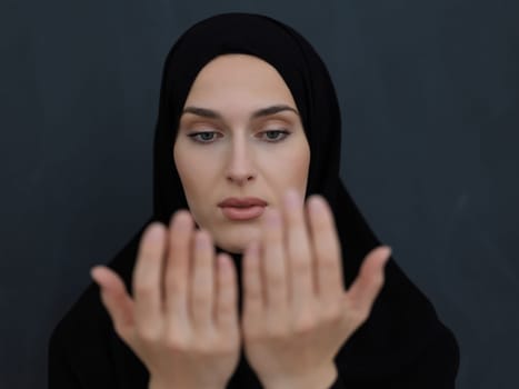 Portrait of young Muslim woman making dua. Arabian girl wearing abaya keeps hands in praying gesture. Representing worship to God and Ramadan Kareem concept