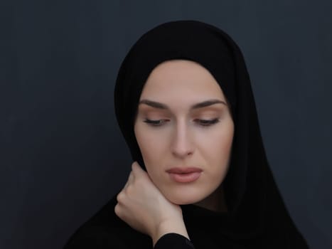Portrait of modern young muslim woman in black abaya. Arab girl wearing traditional clothes and posing in front of black chalkboard. Representing modern and rich arabic lifestyle