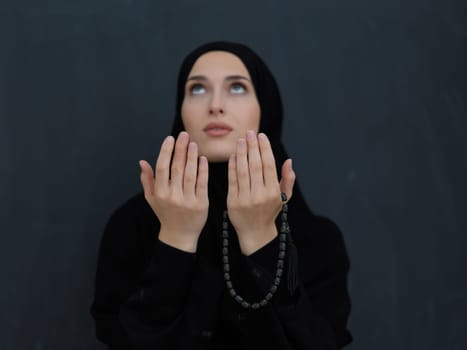 Portrait of young Muslim woman making dua. Arabian girl wearing abaya keeps hands in praying gesture. Representing worship to God and Ramadan Kareem concept