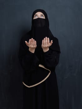 Portrait of young Muslim woman with niqab making dua. Arabian girl wearing abaya keeps hands in praying gesture. Representing worship to God and Ramadan Kareem concept