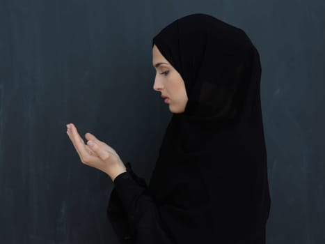 Portrait of young Muslim woman making dua. Arabian girl wearing abaya keeps hands in praying gesture. Representing worship to God and Ramadan Kareem concept
