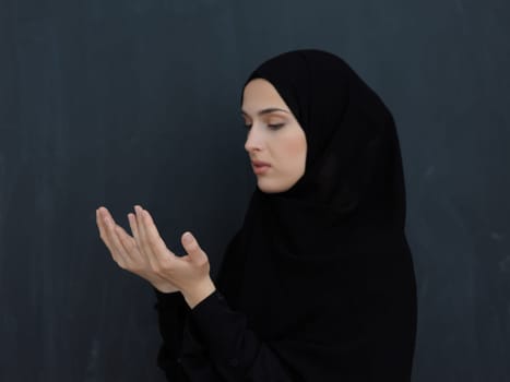 Portrait of young Muslim woman making dua. Arabian girl wearing abaya keeps hands in praying gesture. Representing worship to God and Ramadan Kareem concept