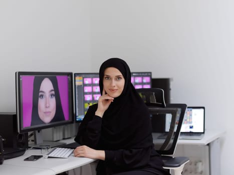 Portrait of young muslim female graphic designer. Hijab girl with the two monitors in background showing her work. Technology concept