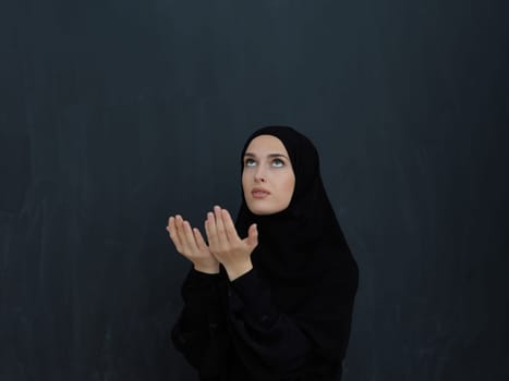 Portrait of young Muslim woman making dua. Arabian girl wearing abaya keeps hands in praying gesture. Representing worship to God and Ramadan Kareem concept