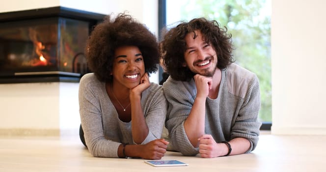 beautiful young multiethnic couple lying on the floor of their luxury home in front of fireplace at autumn day