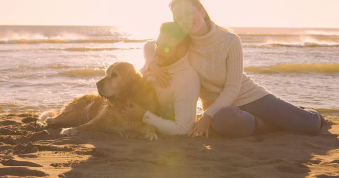 Couple With A Dog enjoying time  together On The Beach at autumn day