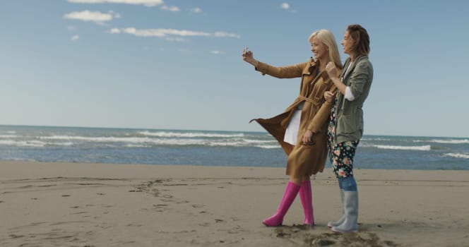 Friends making selfie. two beautiful young women making selfie at autumn day on the beach