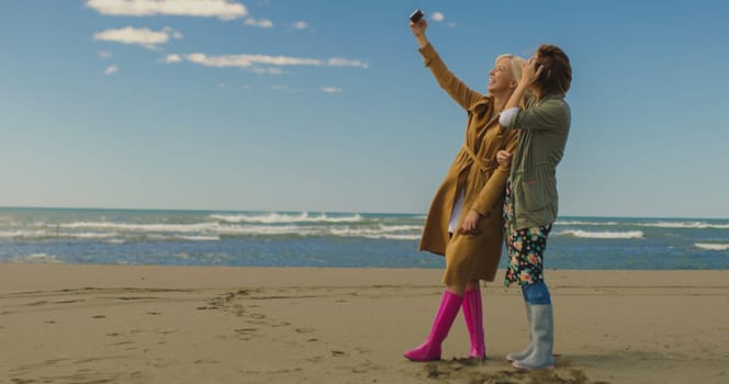 Friends making selfie. two beautiful young women making selfie at autumn day on the beach
