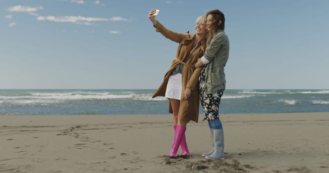 Friends making selfie. two beautiful young women making selfie at autumn day on the beach