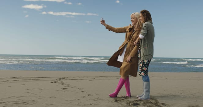 Friends making selfie. two beautiful young women making selfie at autumn day on the beach