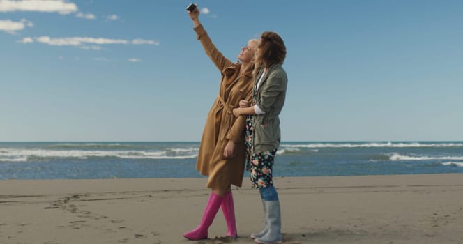 Friends making selfie. two beautiful young women making selfie at autumn day on the beach